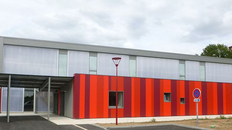 Gymnase vue de l'extérieur: bâtiment rectangulaire gris et rouge