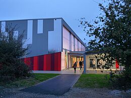 Gymnase vue de l'extérieur: bâtiment rectangulaire gris et rouge