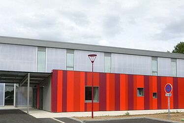 Gymnase vue de l'extérieur: bâtiment rectangulaire gris et rouge