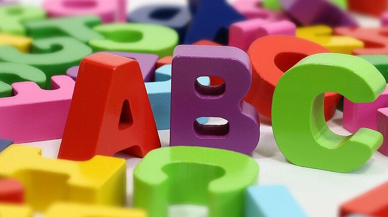 lettres de l'alphabet de toutes les couleurs en relief posé à plat sauf 3 lettres debout: A (rouge), B (violet) et C (vert)