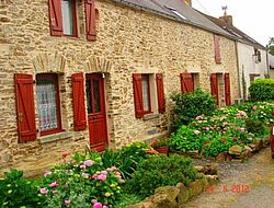 gîte en pierres apparentes, ouvertures bordeaux et plantes verdoyantes