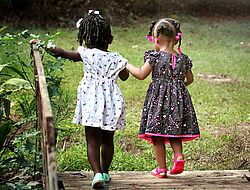 2 petites filles se tiennent par la main: peau de couleur noire et marchent de dos en robe 