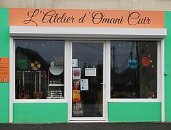 façade du magasin et atelier "Omani Cuir": verte et orange. divers sacs colorés dans la vitrine