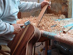 homme en train de fabriquer une guitare en bois